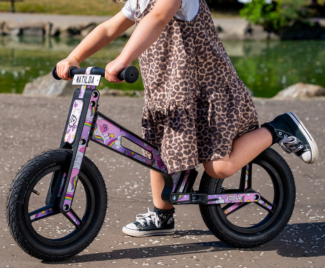 A child riding a Vogue Unicorn Balance Bike, clearly showing the 12" pneumatic air-filled tyres