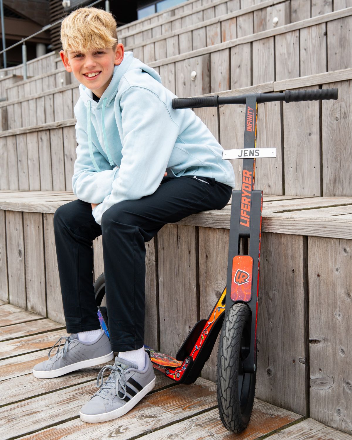Child sitting with a LIFERYDER INFINITY big wheel scooter and mini reg plate